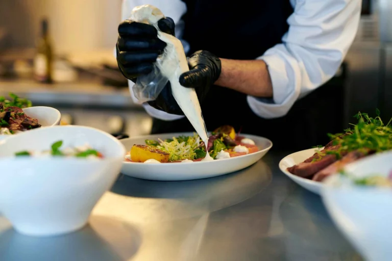 kok sprøjter dressing ud af pose og tilbereder tallerken med fisk
